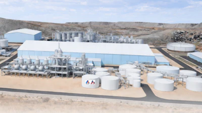 Industrial processing plant with large storage tanks, manufacturing buildings, and equipment in arid landscape