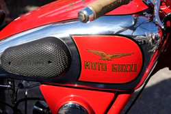 Vintage red Moto Guzzi motorcycle with winged logo on fuel tank and black mesh side panel