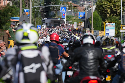 Large crowd gathered on urban street with motorcycles in foreground and commercial signage visible in background