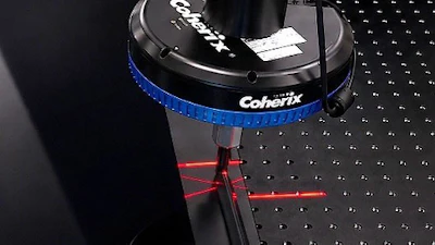 Coherix precision optical equipment with blue collar and red laser alignment marks on optical table