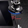 Coherix precision optical equipment with blue collar and red laser alignment marks on optical table