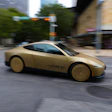 Gold concept sports car with 'Cybertruck' branding driving through urban street with buildings and trees