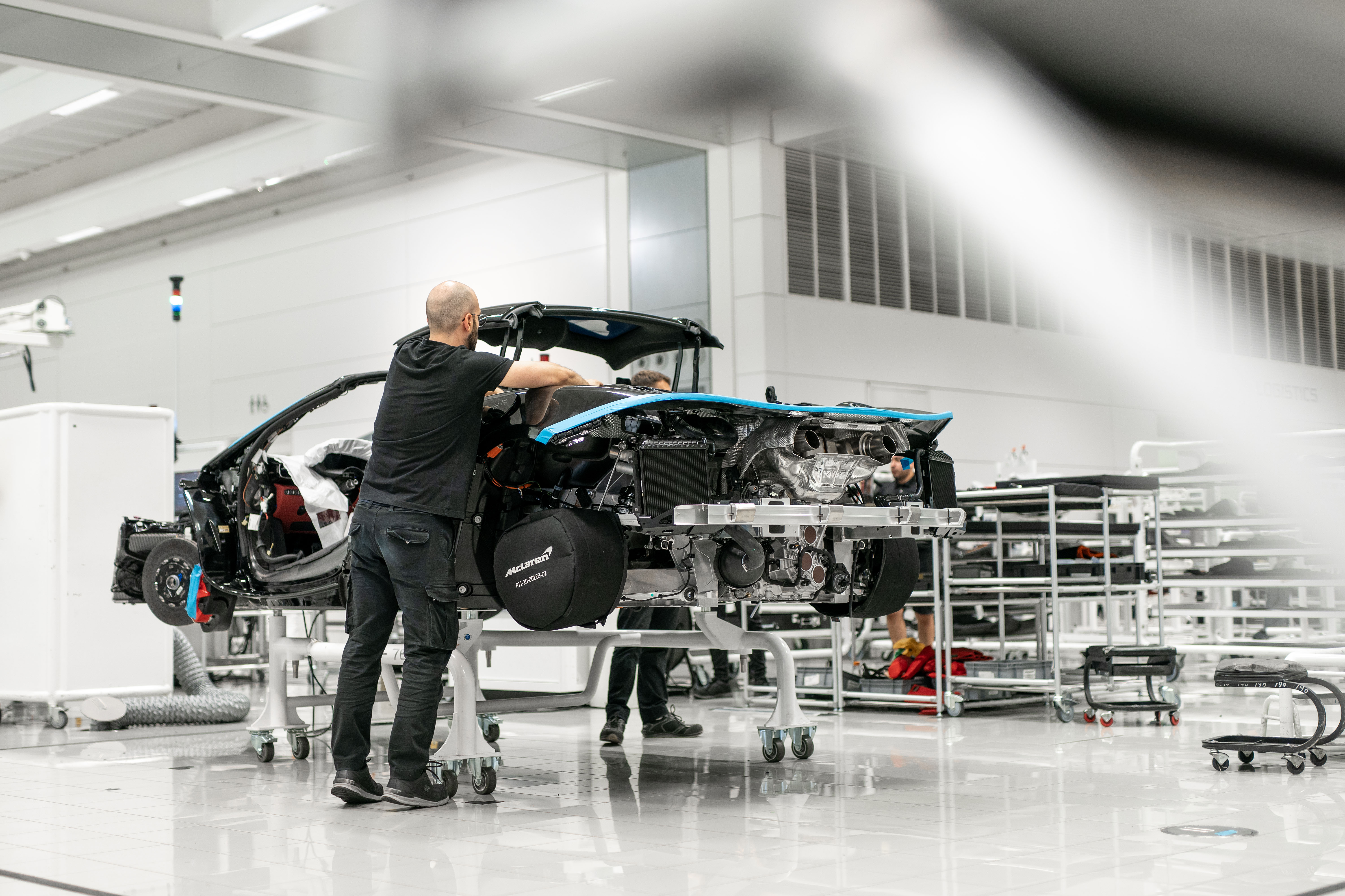 Technician assembling blue sports car engine in modern workshop facility