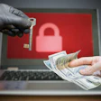Cybersecurity ransom illustration showing gloved hand with key, cash exchange, and padlock on laptop screen