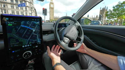 Driver's view from inside a car with GPS navigation display, steering wheel, and London's Big Ben visible through windshield