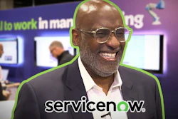 Professional man in glasses smiling at corporate event with ServiceNow branding