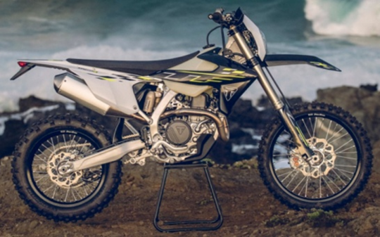 White and black dirt bike motorcycle on stand against cloudy sky and desert landscape