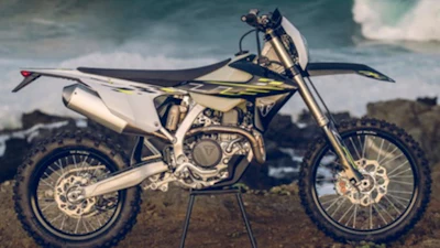 White and black dirt bike motorcycle on stand against cloudy sky and desert landscape
