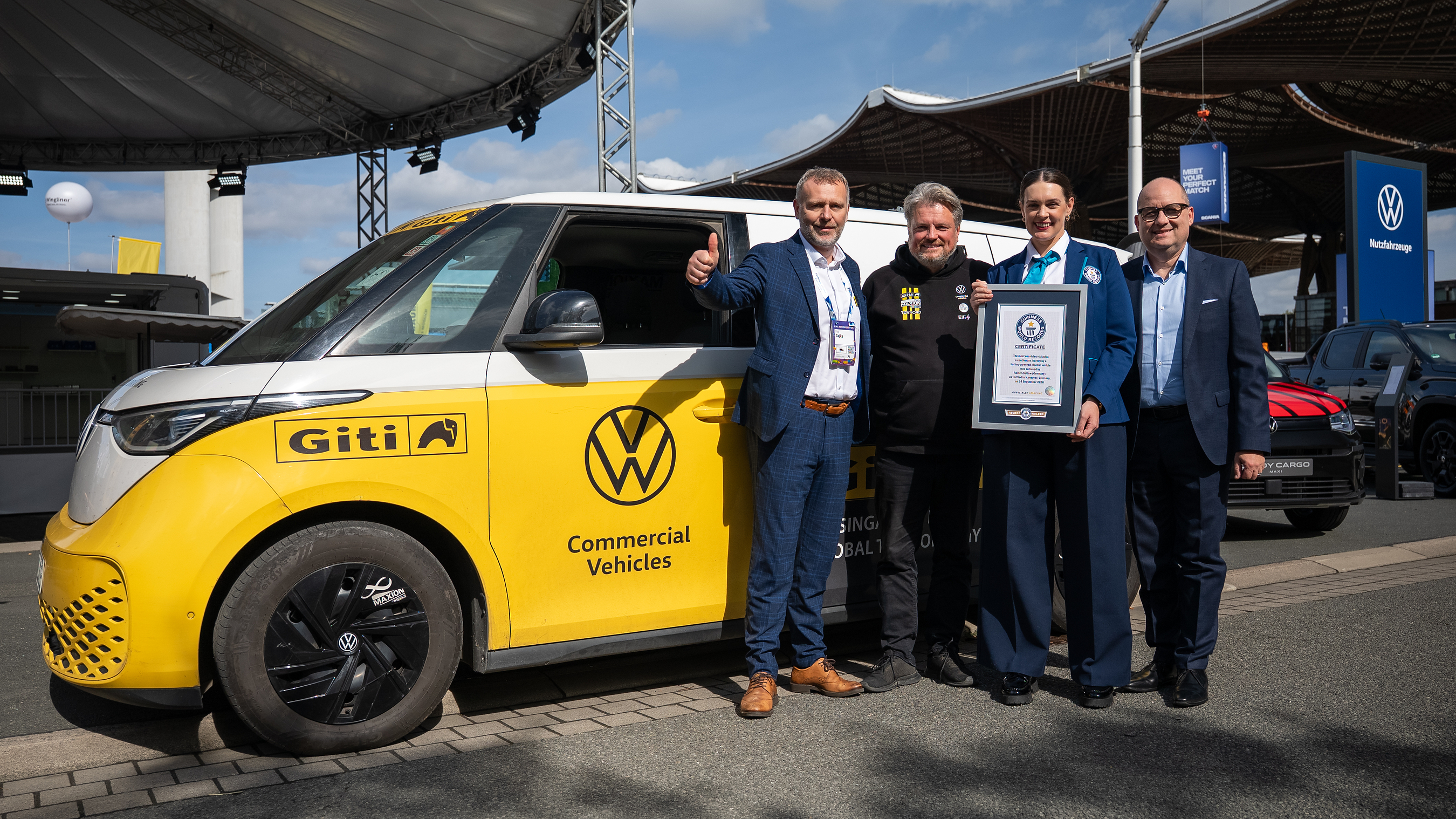 Five men pose with yellow Volkswagen Giti electric commercial vehicle and Guinness World Record certificate at outdoor event