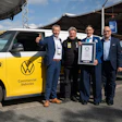Five men pose with yellow Volkswagen Giti electric commercial vehicle and Guinness World Record certificate at outdoor event