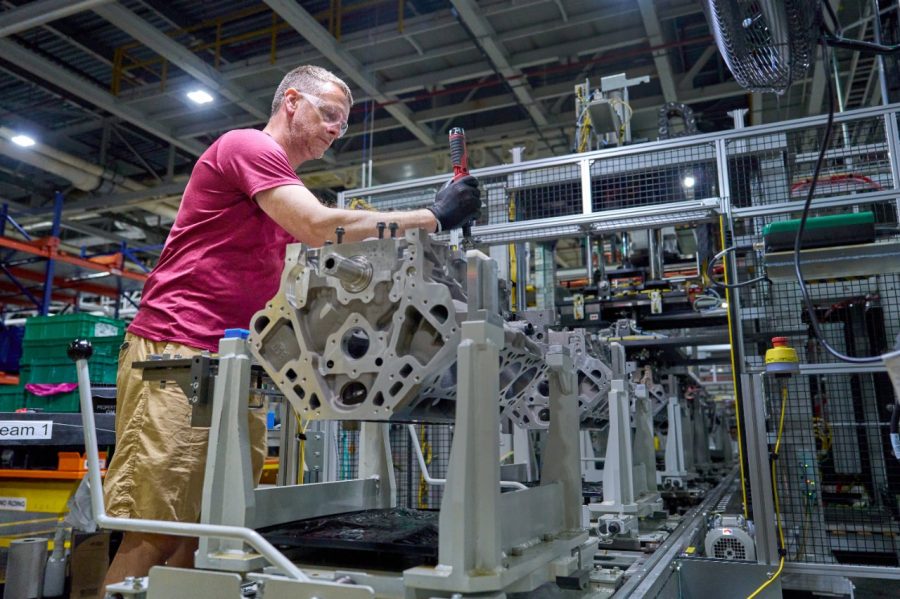 Factory worker assembling engine block on industrial production line