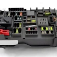 Automotive fuse box with organized yellow and red fuses, relays, and electrical components in black housing