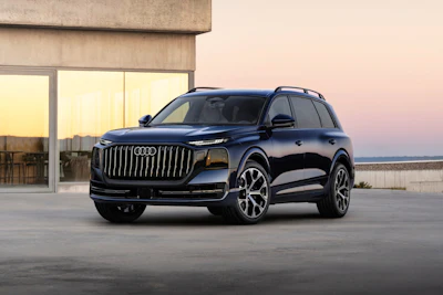 Black Audi luxury SUV parked on a rooftop at sunset with modern building backdrop