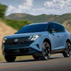 Light blue Nissan Ariya electric SUV driving on a mountain road with scenic hills in the background