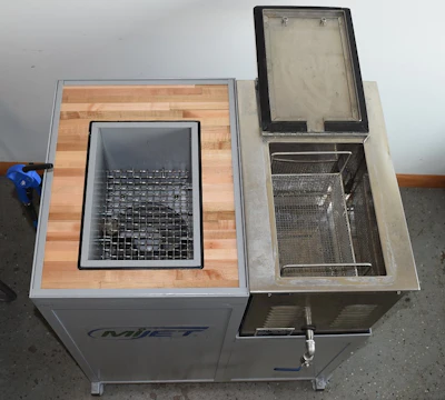 Two OMJET ultrasonic cleaning machines with open lids displaying internal mesh baskets and heating elements