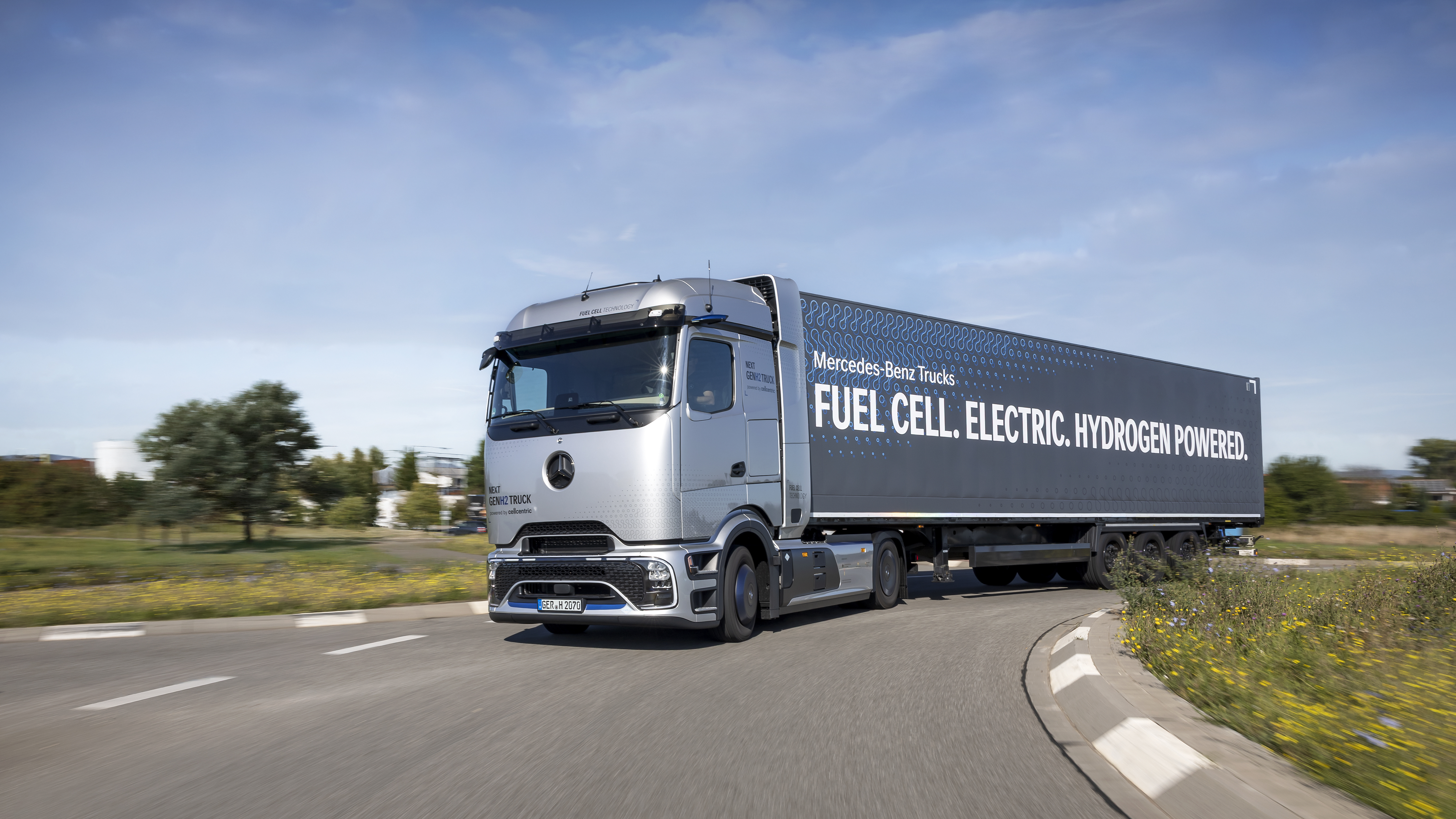 Mercedes-Benz fuel cell electric hydrogen-powered truck driving on highway with green landscape