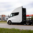 White semi-truck parked at Plas fuel station with open sleeper cab door