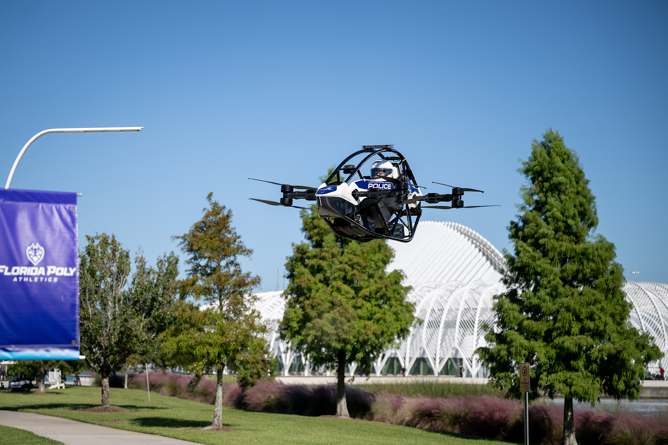Police drone in flight over Florida Poly campus with trees and modern architecture in background