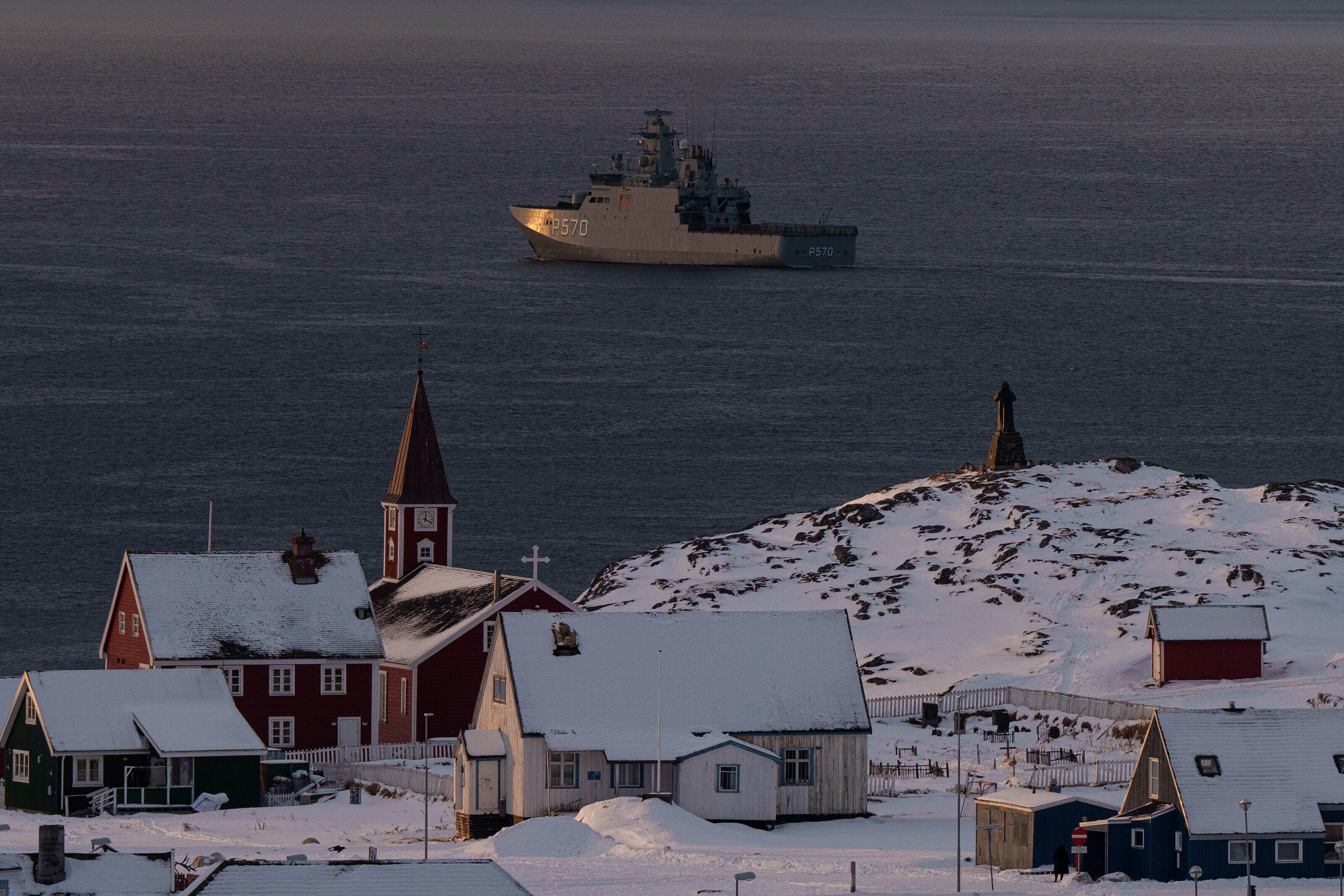 Arctic coastal settlement with red church, snow-covered buildings, and icebreaker ship in Greenlandic waters