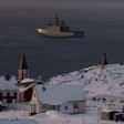 Arctic coastal settlement with red church, snow-covered buildings, and icebreaker ship in Greenlandic waters