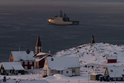 Arctic coastal settlement with red church, snow-covered buildings, and icebreaker ship in Greenlandic waters