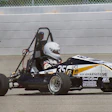 Black and white formula SAE race car with number 35 on concrete track near barrier