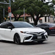 White Toyota Camry sedan parked on urban street with trees and buildings in background