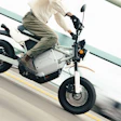Person riding white and black electric scooter on road with yellow lane marking