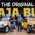 Two men stand between a white and yellow modified Baja Bug vehicles in a garage workshop setting.