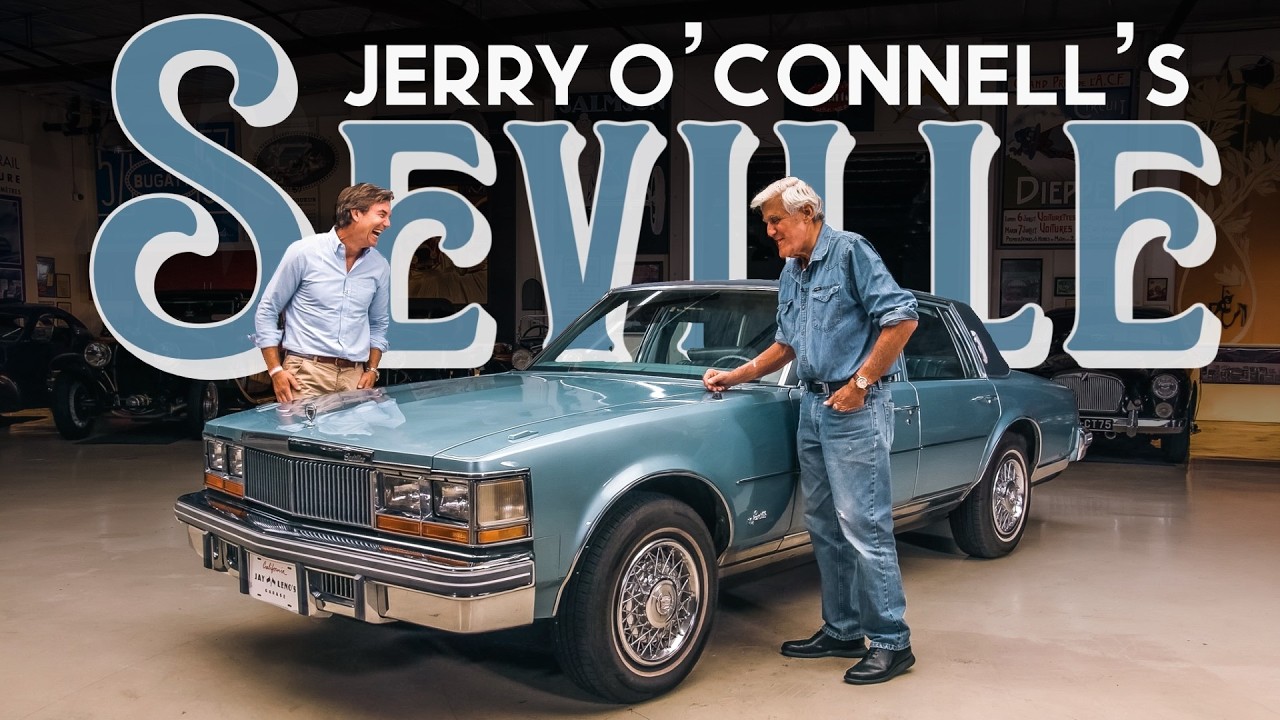 Jerry O'Connell and a man examine a blue classic Oldsmobile Cutlass in a showroom