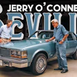 Jerry O'Connell and a man examine a blue classic Oldsmobile Cutlass in a showroom