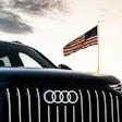 Black Audi vehicle with American flag at sunset