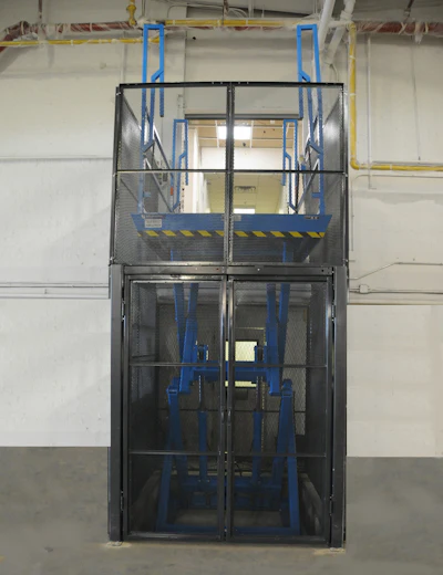 Industrial personnel lift cage with blue frame and safety railings in warehouse facility