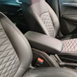 Luxury car interior with quilted leather seats in light gray and black tones, center console visible