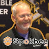 Man speaking at Spokbee corporate event with branded backdrop and logo watermark