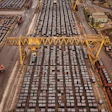 Aerial view of busy shipping port with hundreds of stacked containers, yellow gantry cranes, and cargo handling equipment
